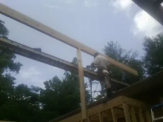 Carpenter setting a ridge beam over a new addition frame — Ice Dam Removal by Roofing Brothers in Grand Haven