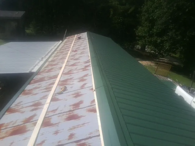 Old rusted panels beside newly installed green metal roofing — Wind Damage Roof Repair by Roofing Brothers in Grand Haven