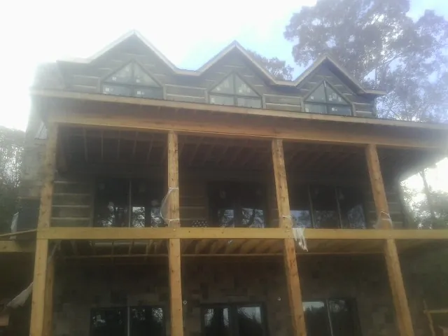 Dormers and porch framing on a large log home under construction — Roof Coating work by our crew in Grand Haven