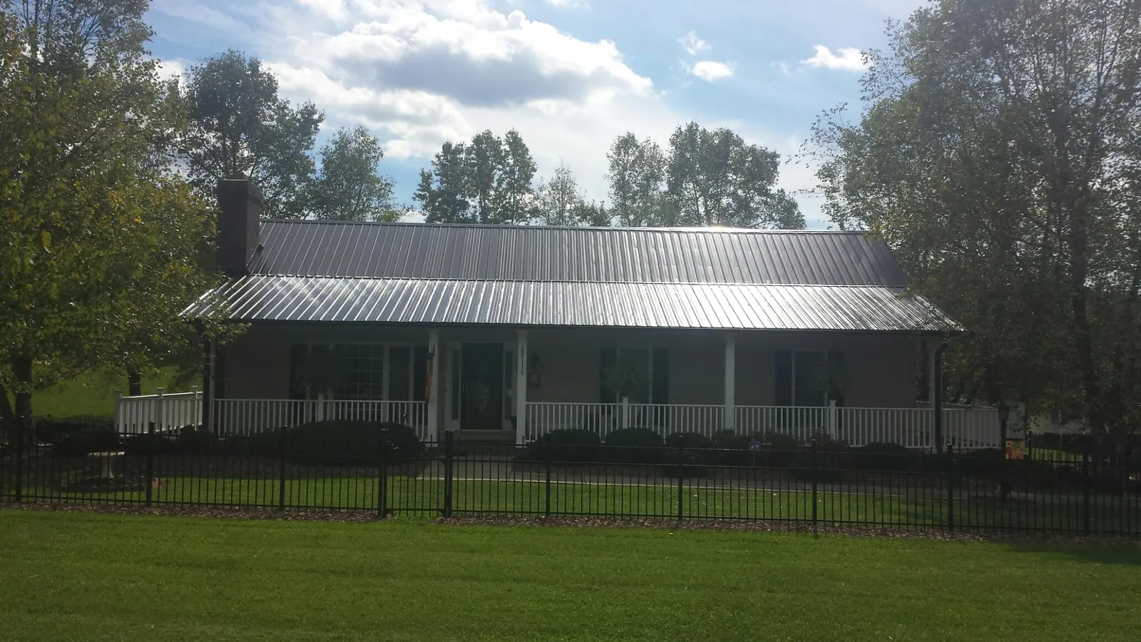Gray metal roof on a brick ranch with a full width front porch — Gutter Guard Installation work by our crew in Grand Haven