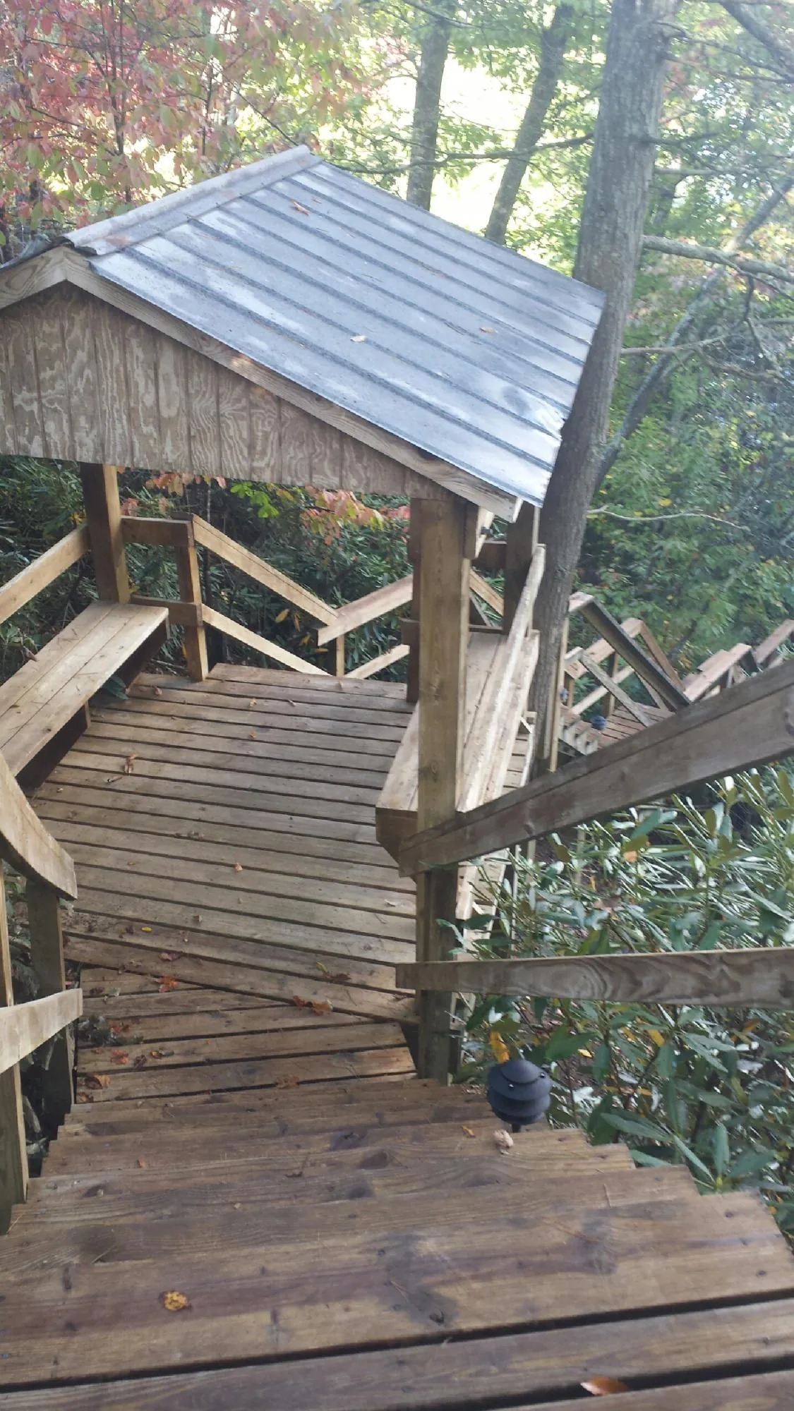 Metal roofed shelter over wooden steps on a wooded walkway — Skylight Repair & Installation work by our crew in Grand Haven