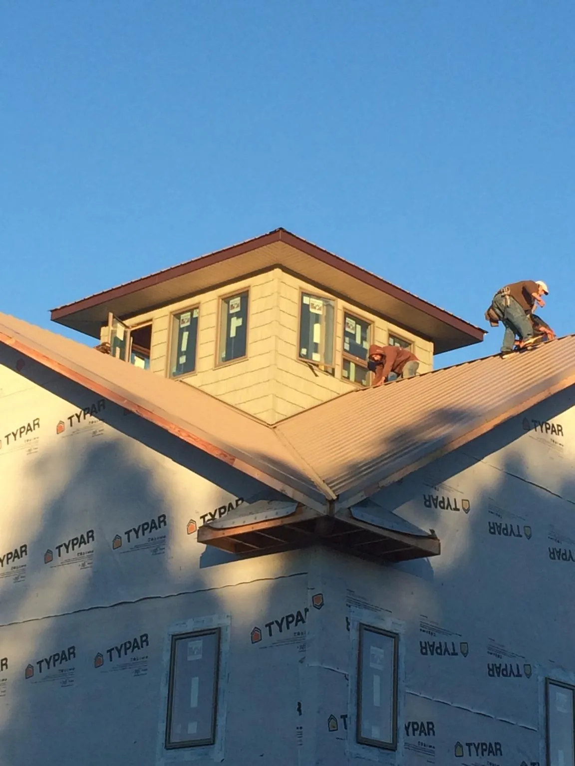 Roofers working around a rooftop cupola on a new metal roof at sunset — Roof Waterproofing in Grand Haven by Roofing Brothers